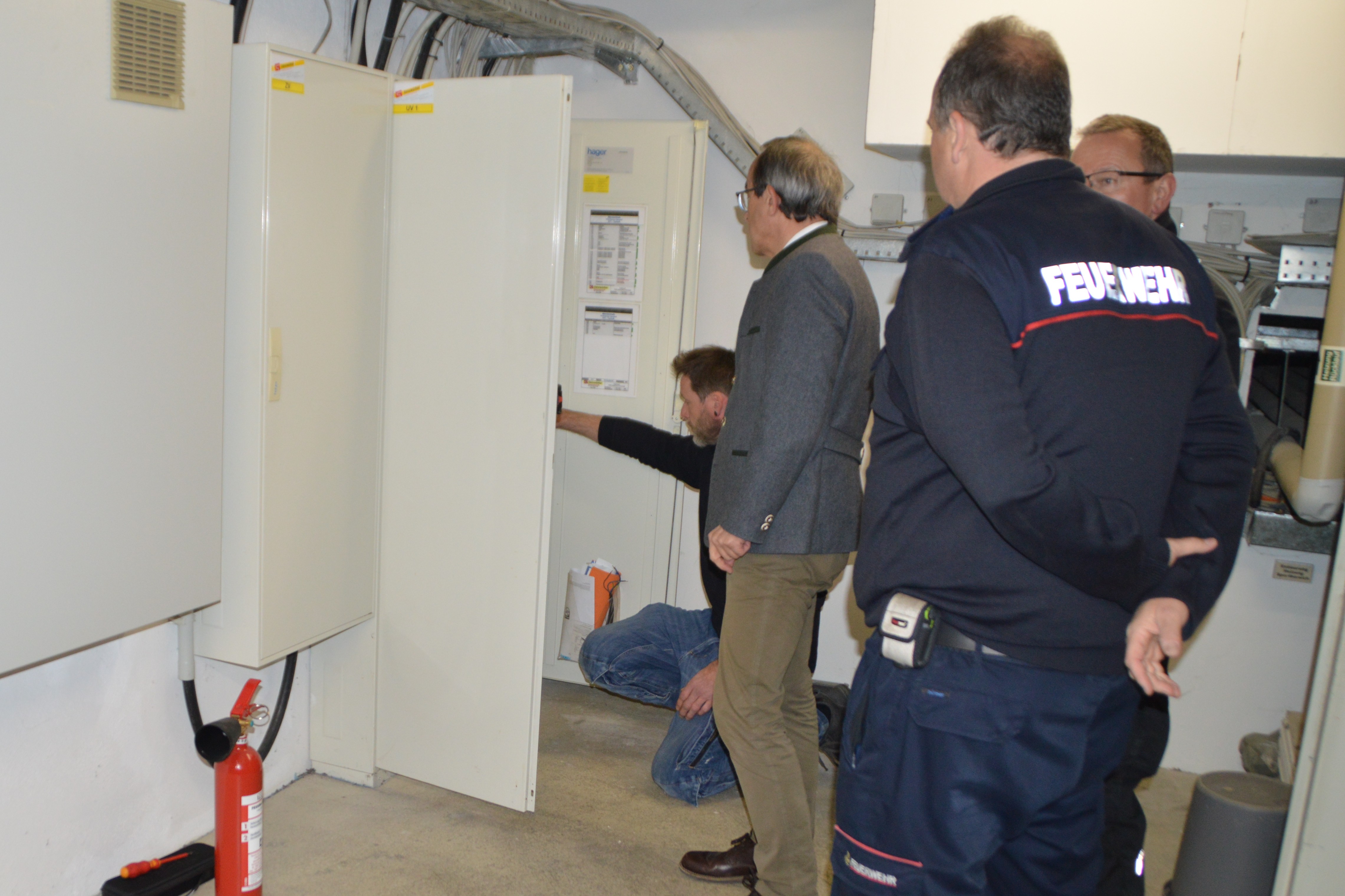 Bürgermeister Roland Burger lässt sich im Beisein von Feuerwehrkommandant And Hollerbach von Tobi Häfner (am Schaltschrank) und Peter Balint die komplexe Haustechnik erklären.
